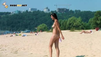 Une adorable jeune fille nudiste se promène sur la plage.